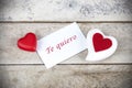 Valentine greeting card on wooden table with text written in spanish Te quiero, which means I love you.