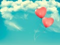 Valentine heart-shaped baloons in a blue sky with clouds.