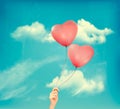 Valentine heart-shaped baloons in a blue sky with clouds.