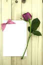 Valentine pink rose and greeting card on wood background.