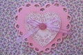 Valentine pink and white lace, doily, ribbon, and button on purple floral fabric heart Royalty Free Stock Photo