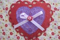 Valentine red and purple lace, doily, ribbon, and button heart on white floral fabric Royalty Free Stock Photo