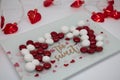 Valentine`s candy tray with red and white candy, heart lights in the background.