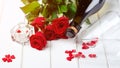 Valentine`s card. Beautiful romantic composition with red roses. Bottle of champagne and roses on white wooden table. Happy Royalty Free Stock Photo