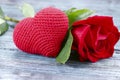 Valentine`s day background. On a gray wooden background in the center is a red knitted heart and a red rose. Royalty Free Stock Photo