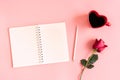 Valentine\'s Day background. Heart shaped cup of black coffee, red rose and notebook on pastel pink background. Royalty Free Stock Photo