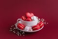 Valentine`s day background with red french heart-shaped macarons and marshmallows. Cup with macarons and marshmallows