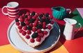 Valentine\'s Day. Berries blackberries and raspberries heart-shaped cake and colored cups on a backgroun