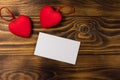 Valentine`s day blank greeting card and two red hearts on wooden background Royalty Free Stock Photo