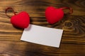 Valentine`s day blank greeting card and two red hearts on wooden background Royalty Free Stock Photo