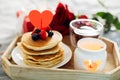 Valentine`s day breakfast or brunch. Homemade pancakes with berries, cup of tea and red roses Royalty Free Stock Photo