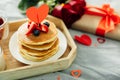 Valentine`s day breakfast concept. Pancakes with berries, roses flowers, cup of tea, gift box Royalty Free Stock Photo