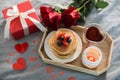 Valentine`s day breakfast concept. Pancakes with berries, roses flowers, cup of tea, gift box and candle in candlestick. Top view Royalty Free Stock Photo