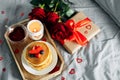 Valentine`s day breakfast concept. Pancakes with berries, roses flowers, cup of tea, gift box and candle in candlestick. Top view Royalty Free Stock Photo