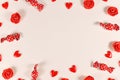 Valentine`s day candy, heart shaped confetti and red roses forming frame around beige background Royalty Free Stock Photo