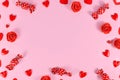 Valentine`s day candy, heart shaped confetti and red roses forming frame around pink background Royalty Free Stock Photo