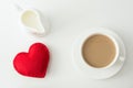 Valentine`s day card. White cup of coffee with milk, red felt heart and milk jug. Top view. Royalty Free Stock Photo