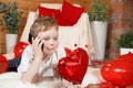 Valentine`s Day children or kids. Cute little boy with a gadget, a mobile phone and a red heart-shaped balloon in his hand, on Royalty Free Stock Photo