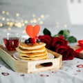 Valentine`s day composition with breakfast, gift box and roses. Stack of delicious pancakes with berries and cup of hot moning te Royalty Free Stock Photo
