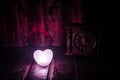 Valentine's Day composition with sweet burning multicolored heart on dark background and old vintage clock, time and love