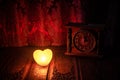 Valentine's Day composition with sweet burning multicolored heart on dark background and old vintage clock, time and love concept,