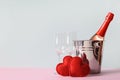 Valentine's day compositon of champagne, two felt hearts, wine glasses on blue.