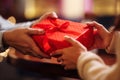 Valentine`s Day concept. Close shot of man`s and woman`s hands presenting gifts to each other at a cafe. A young loving couple Royalty Free Stock Photo