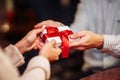 Valentine`s Day concept. Close shot of man`s and woman`s hands presenting gifts to each other at a cafe. A young loving couple Royalty Free Stock Photo