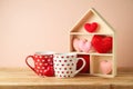 Valentine`s Day concept with coffee cup, house toy and heart shape on wooden table over pink background Royalty Free Stock Photo