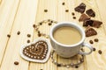 Valentine`s Day concept. Cup of coffee, chocolate, knitted heart, string of pearl beads. Romantic breakfast and gift on wooden