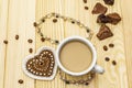 Valentine`s Day concept. Cup of coffee, chocolate, knitted heart, string of pearl beads. Romantic breakfast and gift on wooden