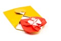 Golden origami envelope with red paper heart lay isolated on white
