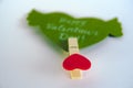Valentine`s day concept. Green paper heart with wings and congratulation fixed on a clothespin on white background. Royalty Free Stock Photo
