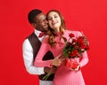 Valentine`s day concept. happy young couple with heart, flowers, gift on red Royalty Free Stock Photo