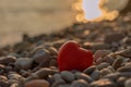 Valentine's Day concept. Red heart romantic love symbol on pebble beach at sunset with copy space. Template for Royalty Free Stock Photo