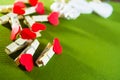 Valentine`s day concept. Red heart shape clothespins and white wooden hearts on green background. Royalty Free Stock Photo