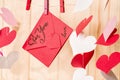Valentine`s day concept. red origami paper envelope hanging on a clip on wooden background with paper hearts around Royalty Free Stock Photo