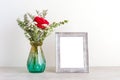 ValentineÃ¢â¬â¢s day concept, Red roses flower bouquet in glass vase and blank grey vintage wooden frame on table background with Royalty Free Stock Photo