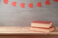 Valentine`s day concept with romantic books on wooden table over garland