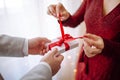 Valentine`s day concept. Side view of a woman opening a giftbox with red ribbon in hands. Loving couple give each other presents Royalty Free Stock Photo