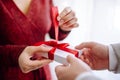 Valentine`s day concept. Side view of a woman opening a giftbox with red ribbon in hands. Loving couple give each other presents Royalty Free Stock Photo