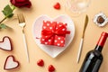 Valentine`s Day concept. Top view photo of heart shaped dish with giftbox with ribbon bow cutlery wine bottle candles wineglass Royalty Free Stock Photo