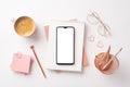 Top view photo of smartphone over notepads pen glasses pink sticky note paper heart shaped clips pencils holder Royalty Free Stock Photo