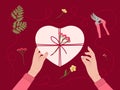 Valentine`s day concept. White female hands hold gift box wrapped into kraft paper. Top view table with romantic eco-friendly Royalty Free Stock Photo
