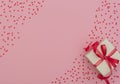 Valentine`s Day concept. White gift box with red ribbon on pink background with lots of small red hearts. Valentine greeting card