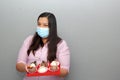 Valentine`s day in contingency covid-19. latin woman with protection mask and chocolate bombs in red ragalo base Royalty Free Stock Photo
