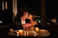 Valentine's day couple kissing at a table with candles and wine, a man gives a woman a gift on a date in the evening in Royalty Free Stock Photo