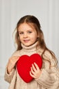 Cute little child girl holding red heart against a white wall Royalty Free Stock Photo