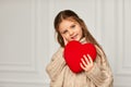 Cute little child girl holding red heart against a white wall Royalty Free Stock Photo