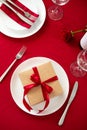 Valentine`s day dining table concept. Plate with gift box, utensil, bottle of wine on red background. Flat lay, top view Royalty Free Stock Photo